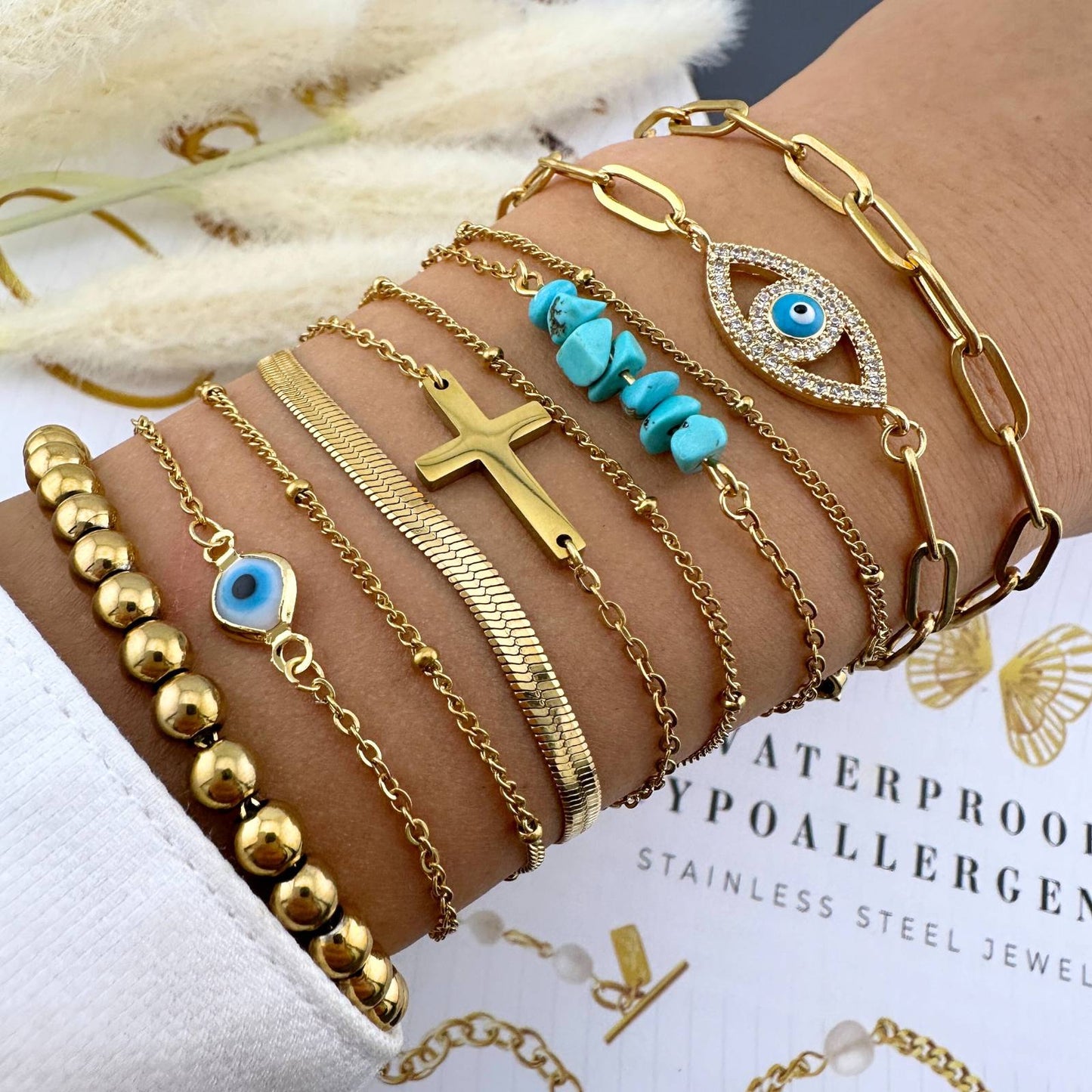 Gold bracelet stack with charms, turquoise, and evil eye designs.