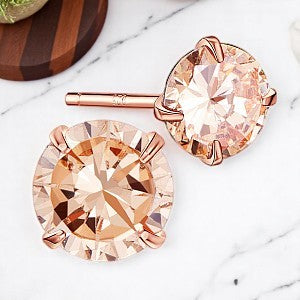 Pair of 4mm round cubic zirconia stud earrings with 18k rose gold plated 925 sterling silver setting, displayed on a marble background.