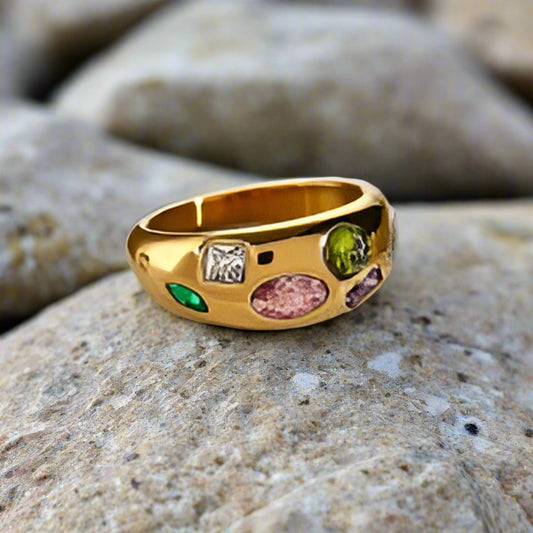 gold multi gemstone ring on a rock